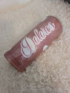 a pink glittered beverage bottle sitting on top of a white carpet with the word bleaves written in cursive font