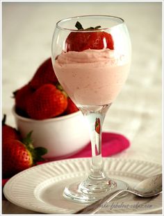 a dessert in a glass with strawberries on the side