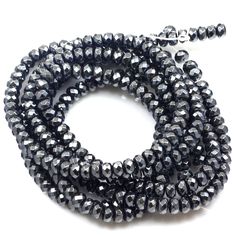 black glass beads are arranged in rows on a white surface