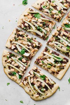 several flatbread pizzas with various toppings cut into squares on a white surface