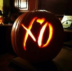 a pumpkin carved to look like the xo symbol is lit up with orange light