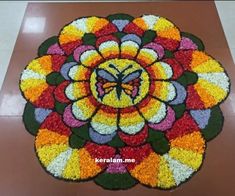 a colorful flower design with a butterfly on the center is made out of flowers and leaves