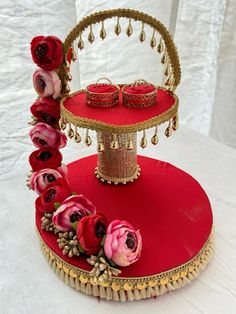 a red tray with flowers on it and two candles in the middle sitting on a white table cloth