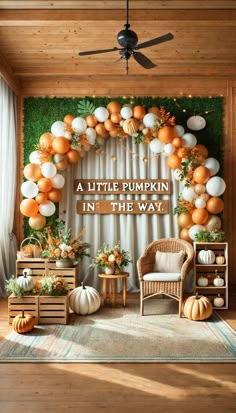 a little pumpkin in the way backdrop with white and orange balloons on it's wall