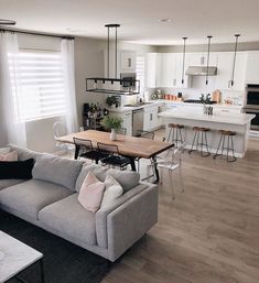 a living room filled with furniture next to a kitchen and dining room table on top of a hard wood floor