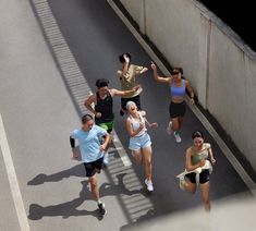 a group of people running down a street next to each other in the middle of the day