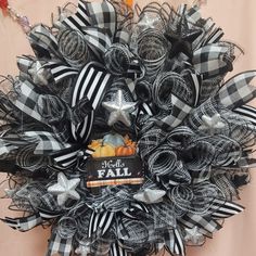 a black and white deco mesh wreath with fall decorations on the front, hanging from a wall