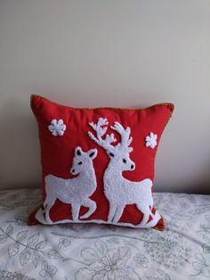 a red pillow with two white deer on it