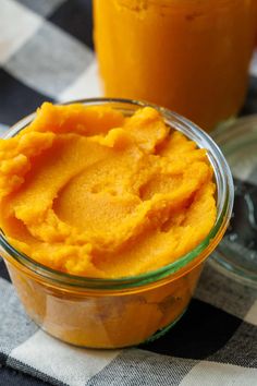 two jars filled with food sitting on top of a checkered table cloth next to orange juice