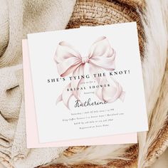 a card with a pink bow on it sitting next to a pile of blankets and pillows