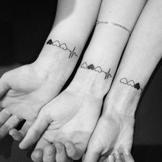 two people holding hands with heartbeat tattoos on their arms and the other hand behind them