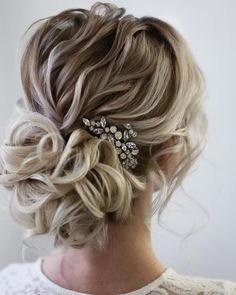 a woman with blonde hair in a messy updo and a crystal brooch on her head