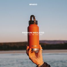 a person holding up an orange water bottle with the words premium insulated on it