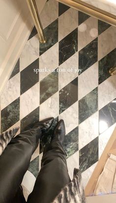 the legs of a person in black and white tile on a floor with gold accents