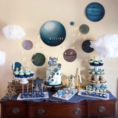 a space themed dessert table with cupcakes, cakes and cookies on it's side