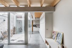 an empty room with wooden ceiling and glass doors leading to the kitchen area is shown