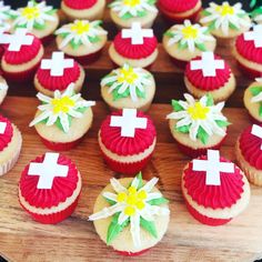 cupcakes decorated with red and white icing on a wooden board, including one for the first