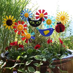 a pot filled with flowers and colorful pinwheels sitting on top of green plants