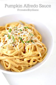 pumpkin alfredo sauce in a white bowl with parmesan cheese and sprinkles