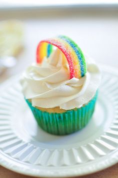 there is a cupcake with white frosting and a rainbow decoration on the top