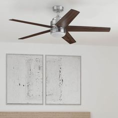 a ceiling fan mounted to the side of a bed in a room with two paintings on the wall