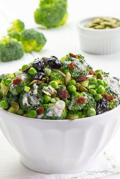 a white bowl filled with broccoli and raisins on top of a table