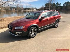 a red volvo suv parked in front of a lake