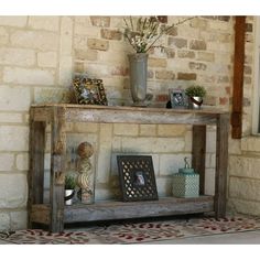 a wooden shelf with pictures on it in front of a brick wall next to a potted plant