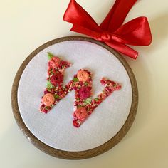 the letter k is made out of flowers and has a red ribbon on top of it