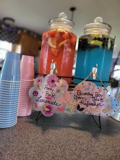 three mason jars filled with drinks sitting on top of a counter next to plates and cups