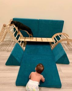 a baby in diapers is playing with a dog on a bed that's attached to a couch