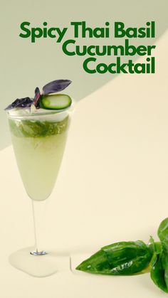 a cocktail with cucumber and basil garnish on the rim next to it