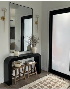 two stools sit in front of a mirror and table with vases on it