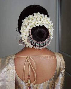 the back of a woman's head with flowers in her hair and jewelry on it