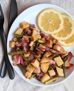 a white plate topped with asparagus, potatoes and lemon wedges next to a fork