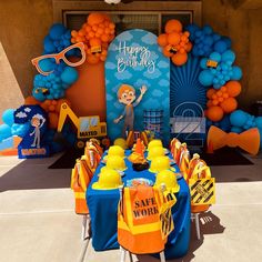 there is a birthday party set up with construction themed decorations on the table and balloons in the background