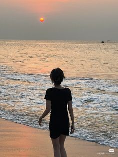 a woman standing on top of a beach next to the ocean