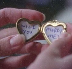 someone holding two hearts that say will you marry me?