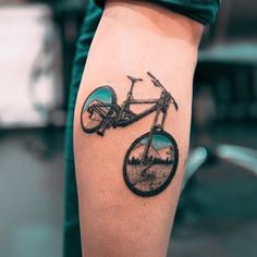 a tattoo on the arm of a person with a mountain bike in front of it