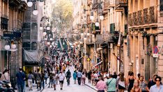 many people are walking down the street in an old city with stone buildings and balconies