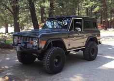 an old jeep is parked in front of some trees