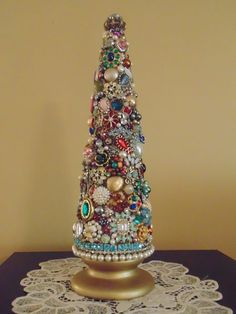 a small christmas tree made out of beads and other items on a doily table