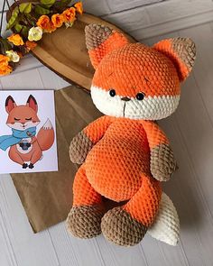 an orange stuffed animal sitting on top of a table next to a card and flowers