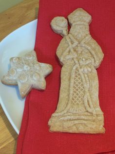 two cookies are on a plate next to a red napkin with an image of a cross