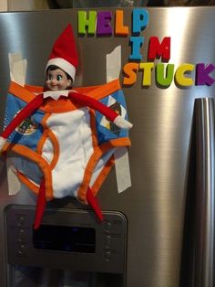 an elf on top of a refrigerator with the words help i'm stuck above it