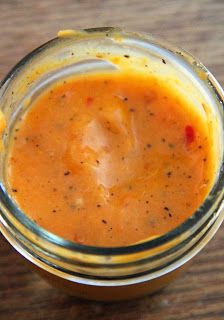 a glass jar filled with sauce on top of a wooden table