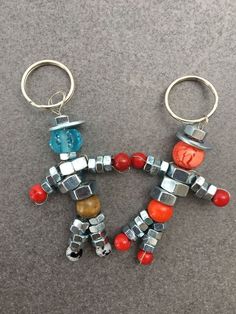 two metal key chains that have different colored beads on them, one is shaped like a man and the other is made out of legos