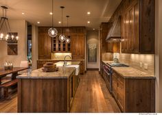 a large kitchen with wooden cabinets and marble counter tops, along with hardwood flooring