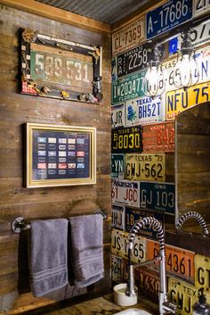 a bathroom with lots of license plates on the wall next to a sink and mirror