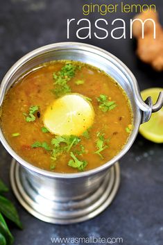 a metal bowl filled with soup and garnished with cilantro, lemon and parsley